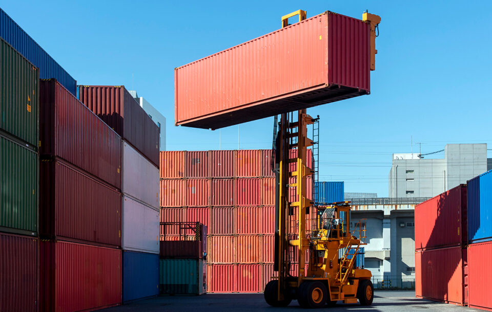En truck lyfter upp en container på ett containerupplag.