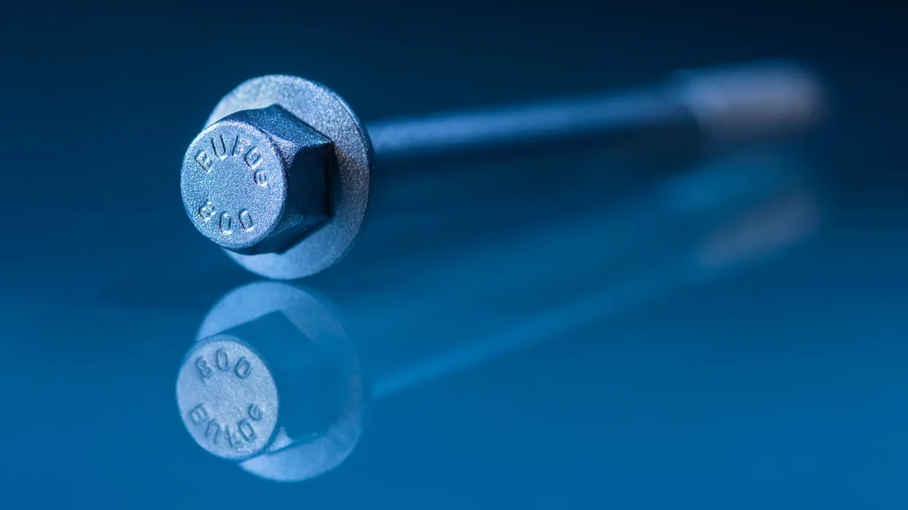 En bult från Bulten. Bulten ligger på en glasyta så att den speglas. Bilden går i blåa toner.