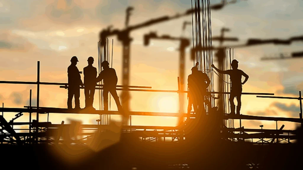 Byggarbetare på en byggarbetsplats i motljus.