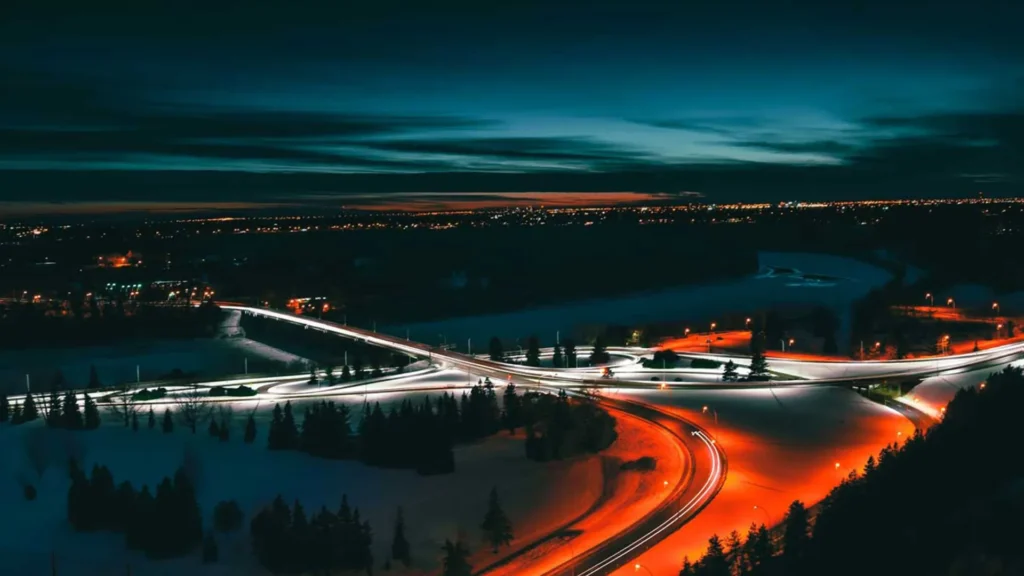 Flygbild på en väg på natten. Röda och vita ljusspår syns från bilarnas lyktor.