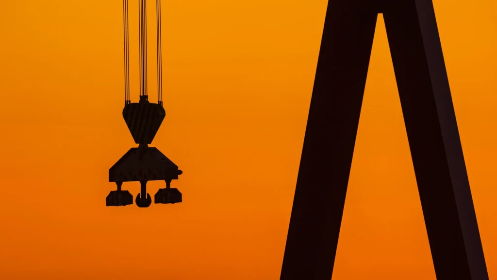 En lyftkran i motljuset av en solnedgång. Himlen glöder i orange.