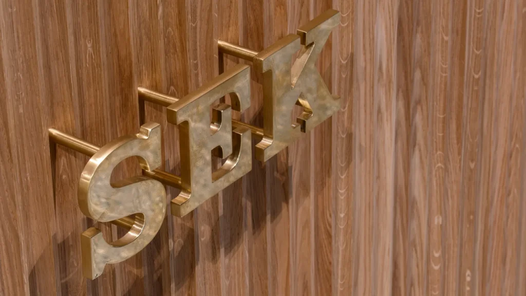 SEK:s logotyp i metall, fäst mot trä.