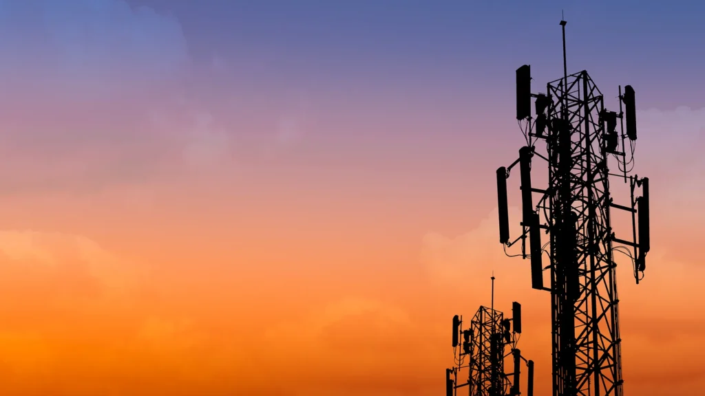 Två telekomtorn sträcker sig mot himlen. Det är solnedgång och himlen lyser i klara färger.