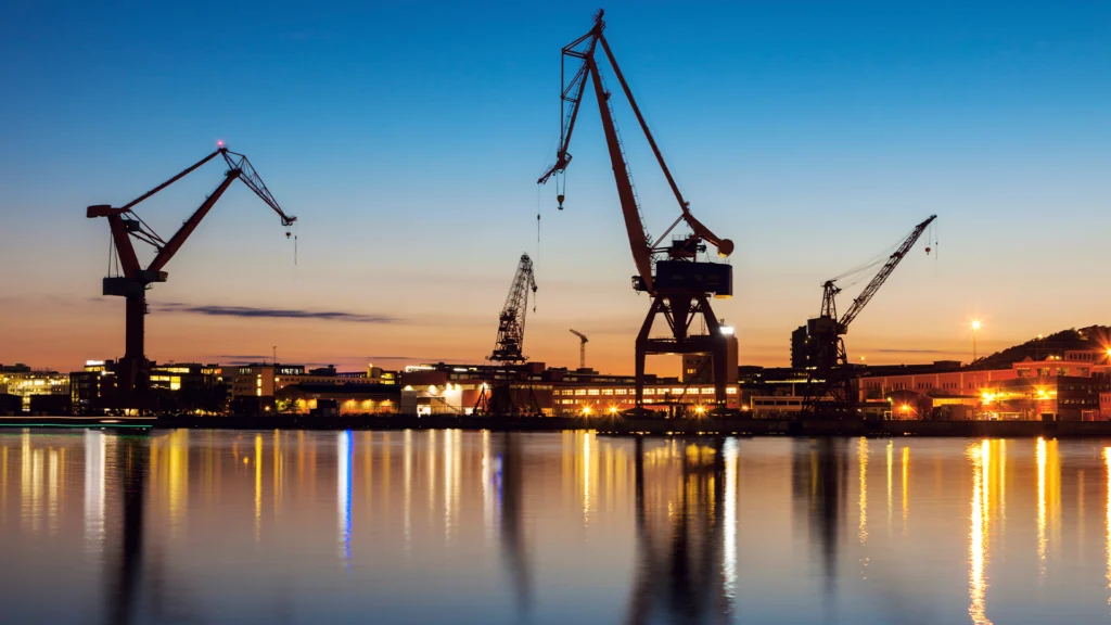 Göteborgs hamn i solnedgång. Lyftkranarna syns som silluetter.